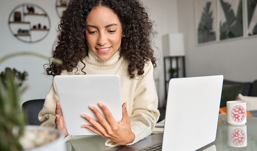 A woman with curly hair examines a tablet, illustrating her interaction with technology.