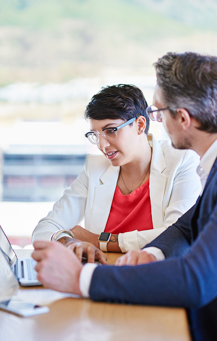 A man and woman collaborate at a table with a laptop, discussing student finance options and strategies.