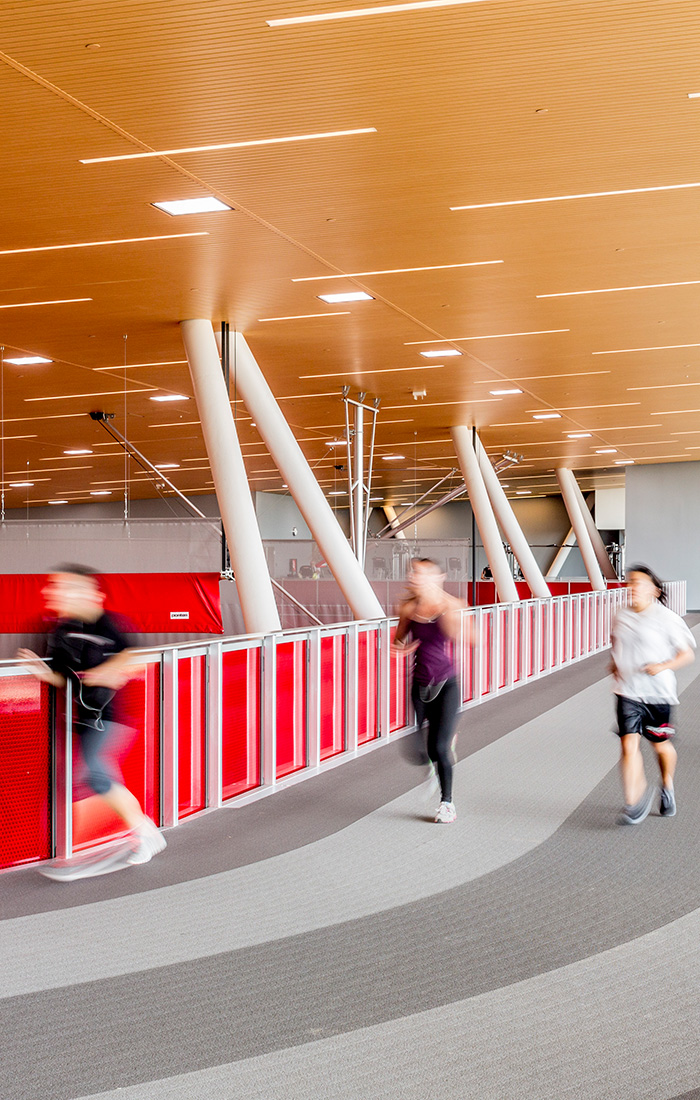 A diverse group of students energetically running through a track in a student recreation center.