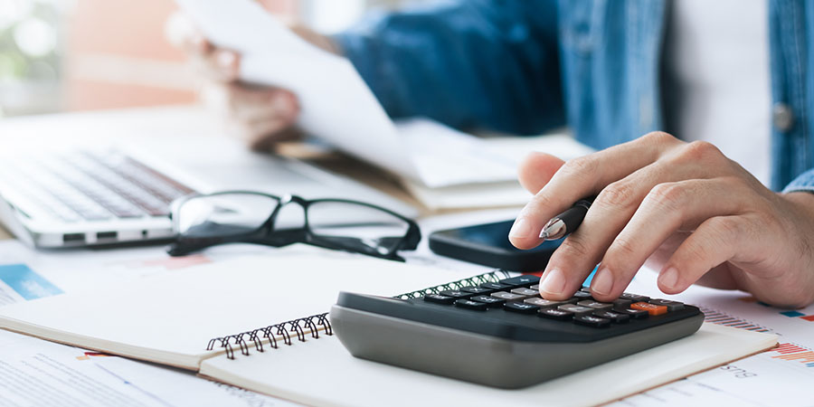 A tax advisor or CPA working on a company’s financials at a desk.